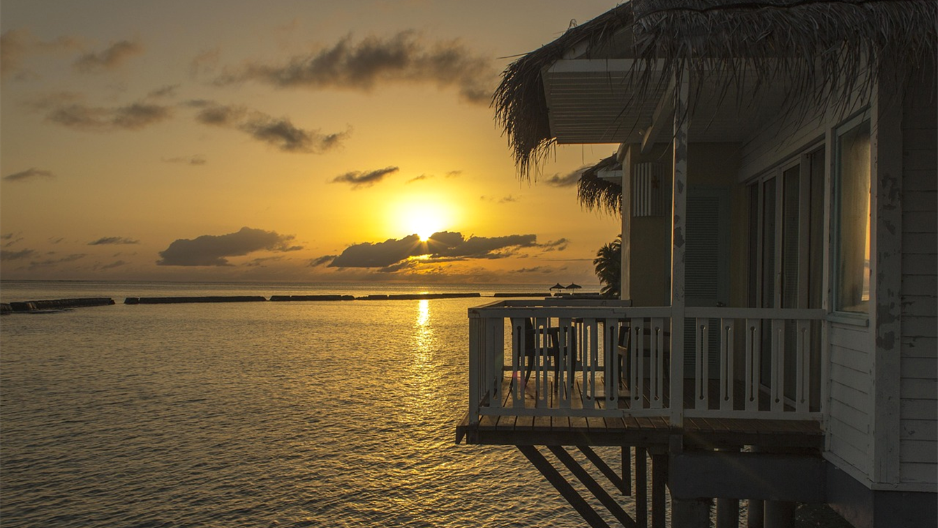 Atardecer sobre el mar junto a un bungalow sobre el agua en Maldivas