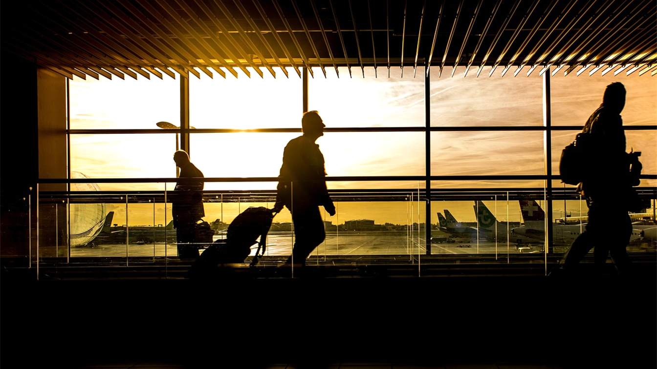 Viajeros con maletas caminando por un aeropuerto al atardecer
